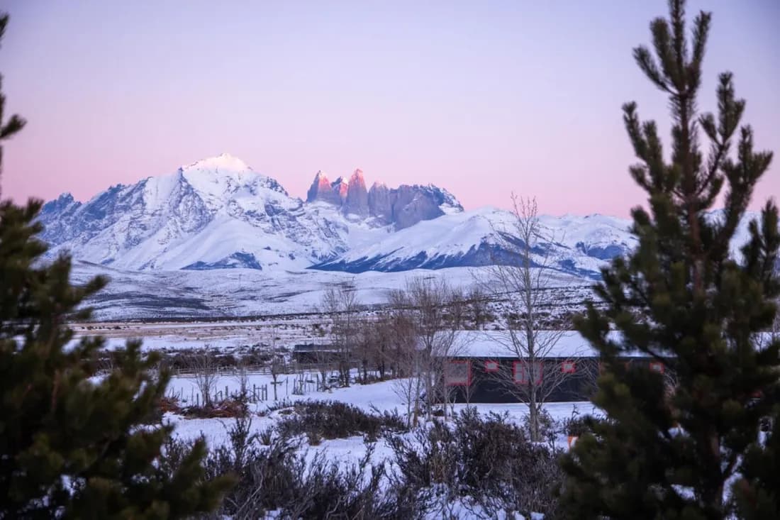 Rasante lodge framed by trees and snowy mountains
