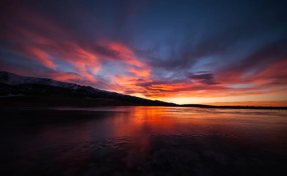 A fiery sunset reflected on a still lake