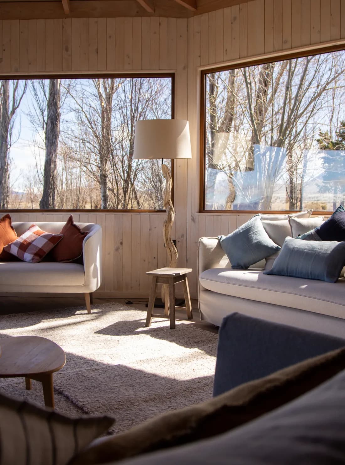The lodge living room, with sofas facing large windows onto the trees