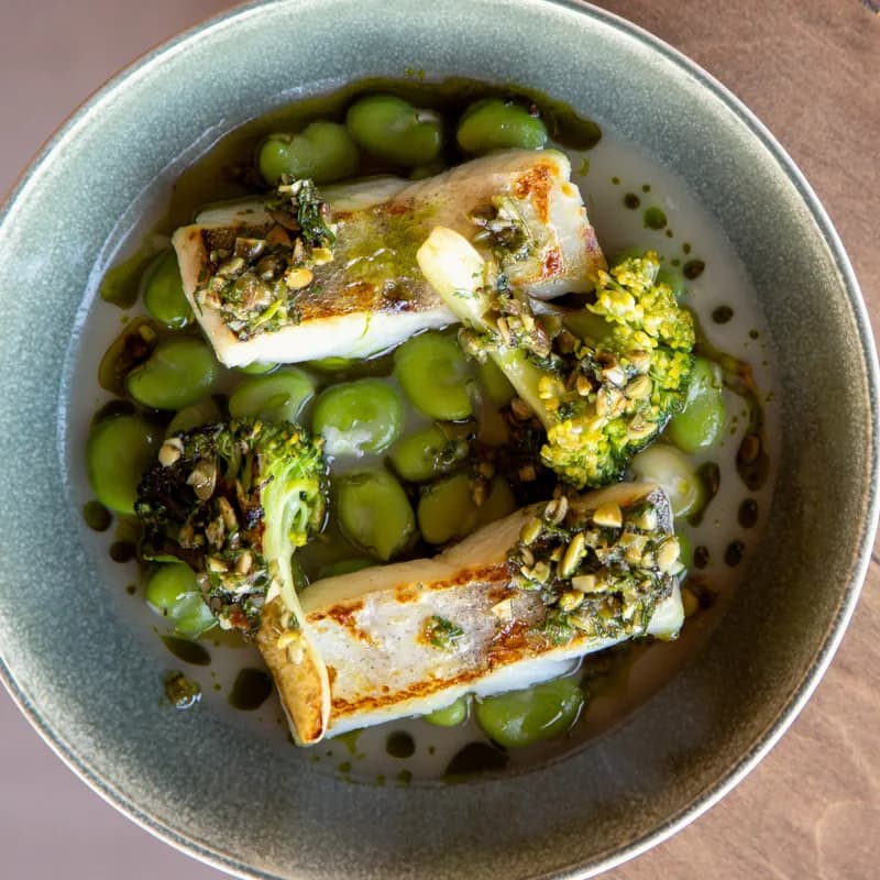 White fish with broad beans and broccoli in a ceramic bowl
