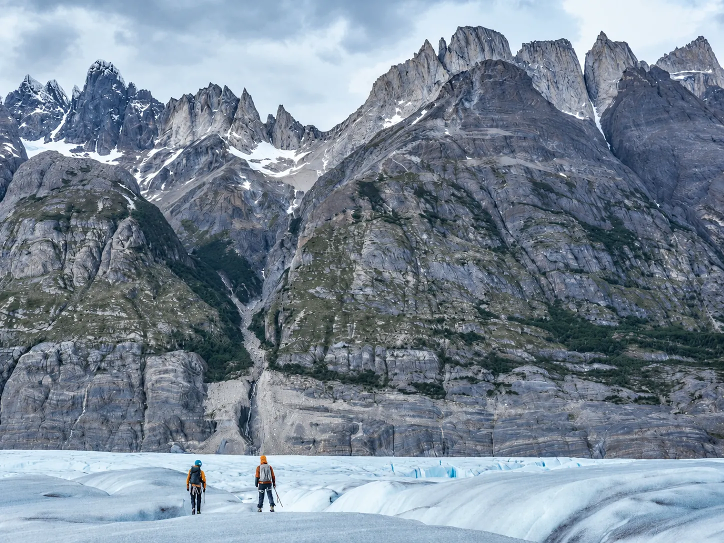 Two hikers crossing a glacier below the granite peaks of Patagonia